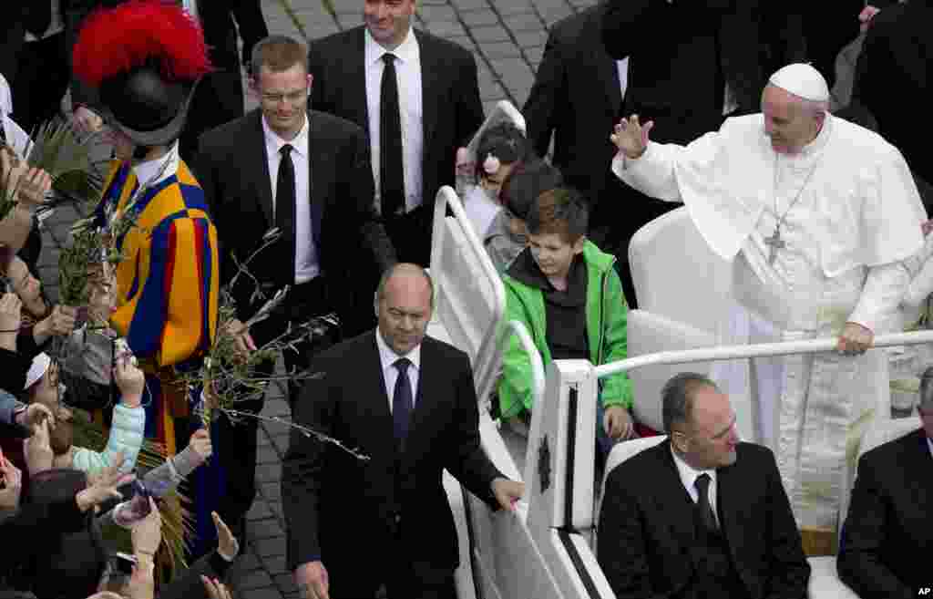 Pope Francis, flanked by children he invited on his pope-mobile, tours St. Peter&#39;s Square at the end of a Palm Sunday Mass, at the Vatican.