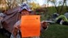 FILE : A homeless woman holds up a notice a police officer gave her giving her 72 hours to move her tent from the park, in Grants Pass, Oregon, April 18, 2024. 