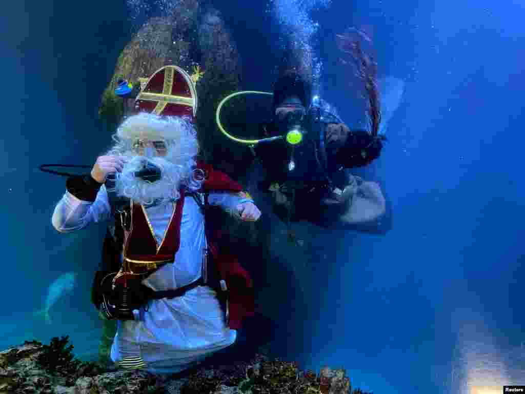 A diver dressed as Santa Claus and his helper &quot;Knecht Ruprecht&quot; pose inside a fish tank at the Sea Life aquarium in Munich, Germany.