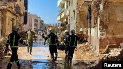 Anggota tim penyelamat dari tentara Mesir membawa mayat korban melewati lumpur di antara bangunan yang hancur akibat badai dan hujan lebat di Derna, Libya, 13 September 2023. (REUTERS/Ahmed Elumami)