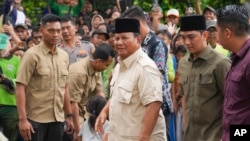 ທ່ານປຣາໂບໂວ ຊູບຽນໂຕ, ກາງ, ເດີນທາງມາຮອດບ່ອນຝັງສົບຂອງພໍາຂອງທ່ານ ໃນນະຄອນຫຼວງຈາກາຕາ, ປະເທດອິນໂດເນເຊຍ, ວັນທີ 15 ກຸມພາ 2024. ອະດີດນາຍພົນ ແລະ ລັດຖະມົນຕີປ້ອງກັນປະເທດຄົນປະຈຸບັນ ເບິ່ງຄືວ່າຈະໄດ້ເປັນປະທານາທິບໍດີຄົນຕໍ່ໄປຂອງປະເທດ, ອີງຕາມຜົນຂອງການລົງຄະແນນສຽງທີ່ບໍ່ເປັນທາງການ. 