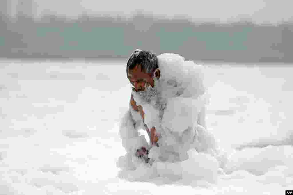 A man bathes in the polluted waters of river Yamuna laden with foam in New Delhi, India.