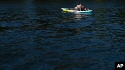 Ljudi se opuštaju na daskama za veslanje na rijeci Willamette u Portlandu, Oregon, 5. jula 2024. Toplinski talas širi se zapadnim dijelom Sjedinjenih Država, šaljući mnoge stanovnike u potragu za hladnim utočištem.