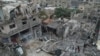 Warga Palestina melihat-lihat di sekitar bangunan yang hancur akibat pengeboman Israel di kamp pengungsi Nuseirat di Jalur Gaza pada Minggu, 29 Oktober 2023. (Foto: AP/Hatem Moussa)