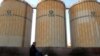 FILE - A man cycles past storage facilities of China's state grain stockpiler Sinograin near Tianjin port, Dec. 12, 2019.
