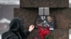 FILE - A woman touches a photo of Alexey Navalny after laying flowers at the Memorial to Victims of Political Repression in St. Petersburg, Russia, on Feb. 17, 2024.