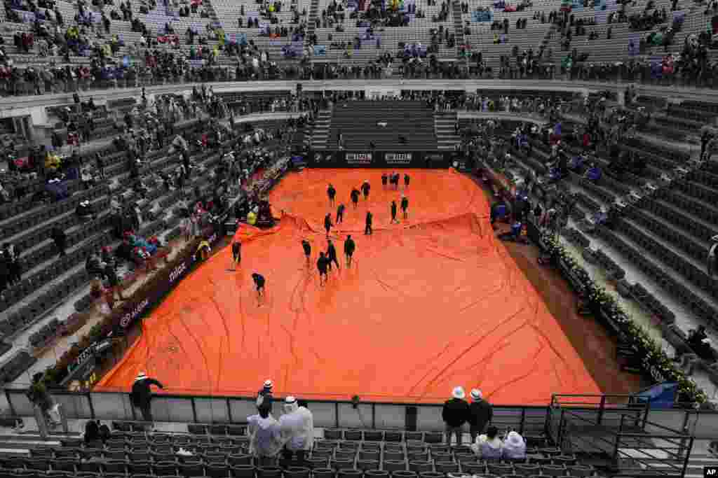 Stewards push water off the rain cover as rain delays the start of the men&#39;s final tennis match between Daniil Medvedev of Russia and Denmark&#39;s Holger Rune at the Italian Open tennis tournament in Rome, Italy.