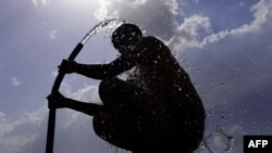 ภาพเงาชายคนหนึ่งในอินเดียใช้สายยางฉีดน้ำอาบกลางแดด ท่ามกลางสภาพอากาศร้อนจัด