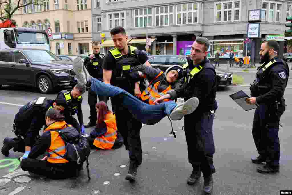 Police officers carry away an activist of the &quot;Letzte Generation&quot; (Last Generation), who previously glued himself to a street at Steglitz district to protest for climate councils, a speed limit on highways as well as for affordable public transport, in Berlin, Germany.