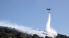 A firefighting helicopter throws water over a wildfire at Keratea area, southeast of Athens, Greece, June 30, 2024. 