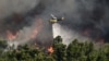 A firefighting helicopter makes a water drop as a wildfire burns in Varnava, near Athens, Greece, Aug. 11, 2024. 