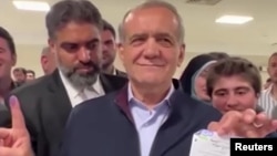 FILE - Iranian presidential candidate, Massoud Pezeshkian holds up inked finger after voting in Tehran, Iran, June 28, 2024.
