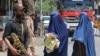 ແມ່ຍິງທີ່ນຸ່ງຜ້າປົກຫົວ burqa-clad ຍ່າງຜ່ານ ເຈົ້າໜ້າທີ່ຮັກສາຄວາມປອດໄພຕາລິບານ ຢູ່ຕາມຖະໜົນໃນເມືອງ ຈາລາລາລາບັດ ໃັນທີ 30 ເມສາ 2023. 