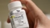 FILE - A pharmacist holds a bottle OxyContin made by Purdue Pharma at a pharmacy in Provo, Utah, May 9, 2019. On Tuesday, Purdue Pharma received U.S. court approval for a 60-day freeze on lawsuits against its owners, the Sackler family.