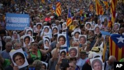 Supporters of Catalan independence leader Carles Puigdemont hold his portrait as they wait for his arrival near the Catalan parliament in Barcelona, Spain, Aug. 8, 2024.