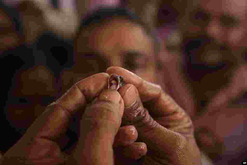 A member of the Goud family opens a fish&#39;s mouth to insert herbal medicine before administering it to a patient, in Hyderabad, India. Every year thousands of asthma patients arrive to receive the fish therapy from the Bathini Goud family, a secret formula of herbs, handed down by generations only to family members. The herbs are inserted in the mouth of a live sardine, or murrel fish, and slipped into the patient&#39;s throat.