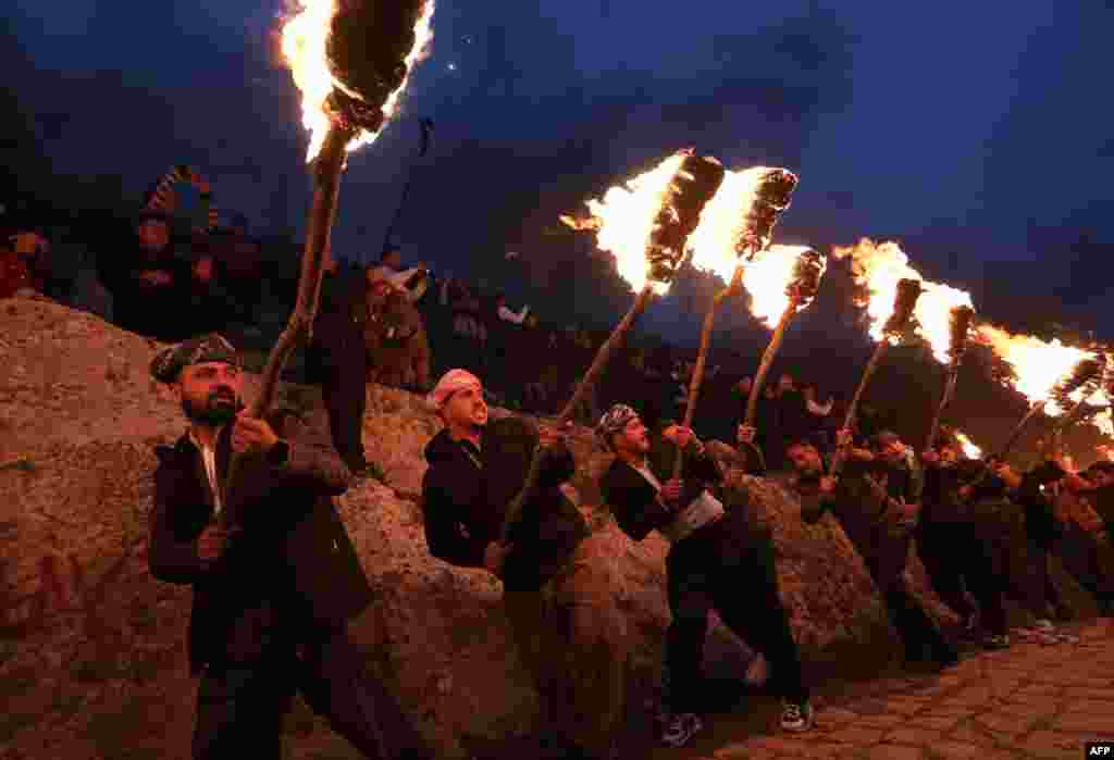 Iraqi Kurds holding torches walk up a mountain during a procession to celebrate their Nowruz New Year festival in Akre, the country&#39;s northern autonomous Kurdish region, March 20, 2023.