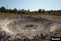 Local residents look at a crater that appeared during a Russian missile strike outside of Kyiv, Ukraine, Aug. 18, 2024.