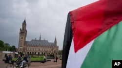 Demonstrant maše palestinskom zastavom ispred Palate mira u kojoj se nalazi Međunarodni sud pravde u Hagu, Holandija, 24. maja 2024. Sud UN-a naredio je Izraelu da obustavi svoje vojne operacije u Gazi.