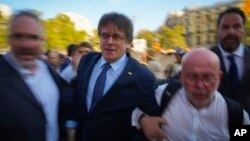 Catalan independence leader and former President Carles Puigdemont, center, arrives to address supporters near the Catalan parliament and to attend the investiture debate afterwards in Barcelona, Spain, Aug. 8, 2024.