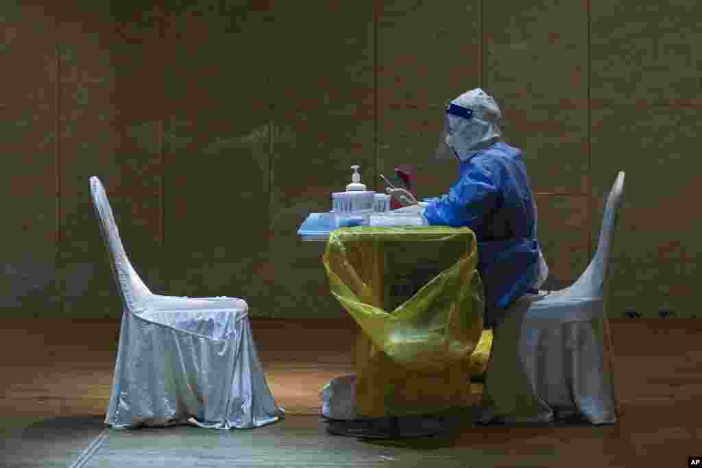 A medical worker in protective gear waits to administer COVID-19 tests for reporters&nbsp;who signed up to cover the press conference and the opening of the Chinese People&#39;s Political Consultative Conference&nbsp; at a quarantine hotel in Beijing.