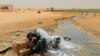 Un migrant d'origine africaine boit de l'eau à son arrivée dans une zone inhabitée près d'al-Assah à la frontière libyo-tunisienne le 30 juillet 2023.