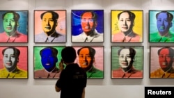 FILE - A visitor looks at a 10-piece set paper screenprint of Mao Zedong by Andy Warhol, which is part of Warhol's series of the late Chinese leader, displayed at the Hong Kong Convention and Exhibition Center, May 26, 2008. 