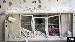 Palestinsko dijete gleda kroz prozor zgrade oštećene u izraelskom napadu na izbjeglički kamp Nuseirat u središnjem pojasu Gaze, 6. jula 2024.