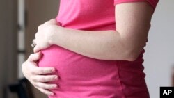 FILE - A pregnant woman stands for a portrait in Dallas, Texas, May 18, 2023. Thirteen women accused of illegally acting as surrogate mothers in Cambodia after being recruited online could face prison after giving birth, a Cambodian official said Saturday. 