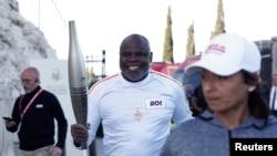 Bivši francuski fudbaler Basile Boli drži olimpijsku baklju tokom štafete uoči Olimpijskih igara u Parizu 2024. u Marseju, Francuska, 9. maja 2024.