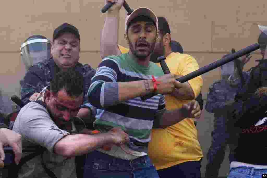 Bank security personnel and riot police attack an injured protesting depositor outside a Bank Audi branch in downtown Beirut, Lebanon.&nbsp;Depositors for years have protested at the banks, demanding their trapped savings back, as they struggle amid an economic crisis that has plunged upwards of three-quarters of the tiny country&#39;s population into poverty.