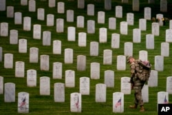 Pripadnik 3. američkog pješadijskog puka postavlja zastave ispred svakog nadgrobnog spomenika za "Flags-In" na Arlington nacionalnom groblju u Arlingtonu, 25. maja 2023., u čast palim vojnim herojima nacije uoči Dana sjećanja.
