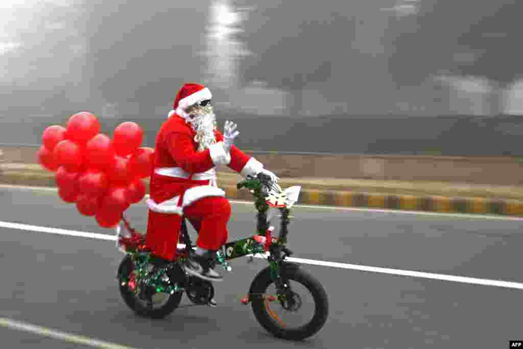 Santa Claus rides a cycle along a street engulfed in fog on Christmas in New Delhi, India.