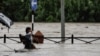 A woman carrying her belongings wades through a flooded road along the bank of overflowing Bagmati River following heavy rains in Kathmandu, Nepal, July 6, 2024. 