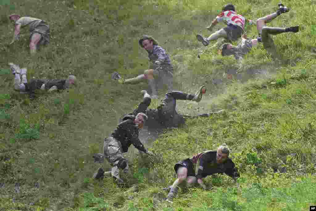 Participants compete in the men&#39;s downhill race during the Cheese Rolling contest at Cooper&#39;s Hill in Brockworth, Gloucestershire.