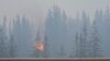 FILE - Flames and smoke rise from a wildfire visible from a highway in Jasper, Alberta, Canada, July 23, 2024, in this screen grab from a social media video. (Donald Schroll via Reuters)