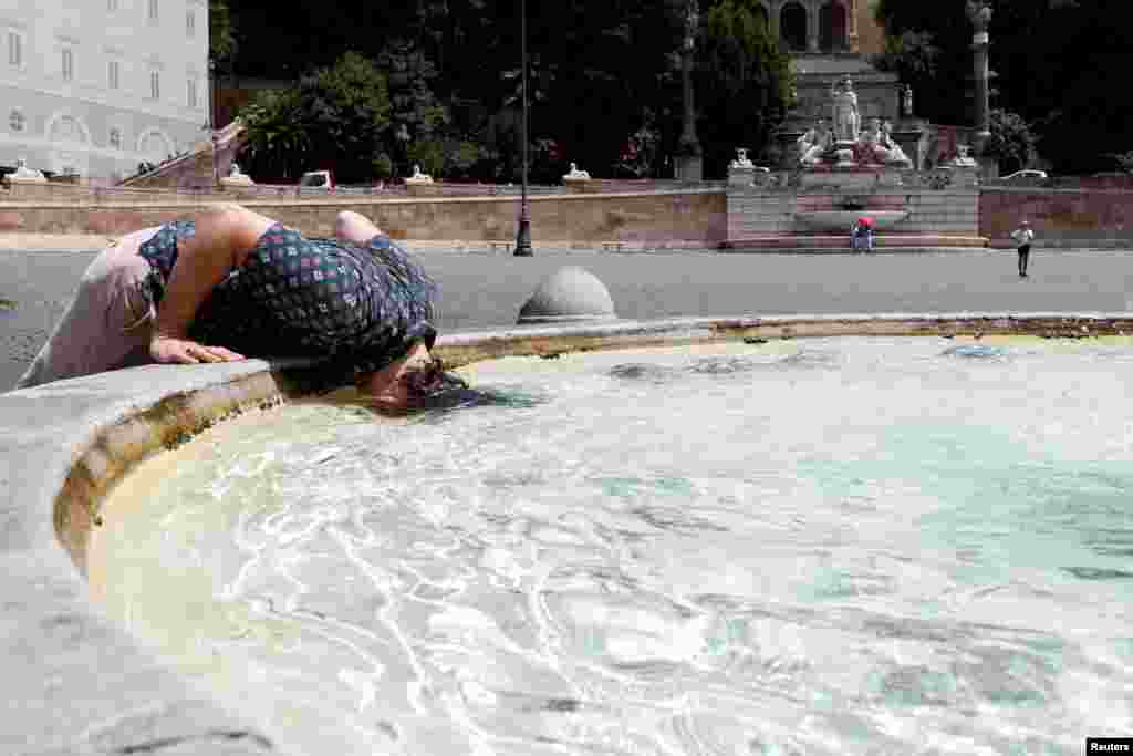 A person cools off at the Piazza del Popolo in Romeas while a heatwave bakes Italy as temperatures are expected to rise further in the coming days.