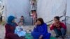 A Syrian family sits in front of their tent at a refugee camp in the town of Bar Elias, in Lebanon's Bekaa Valley, June 13, 2023. 