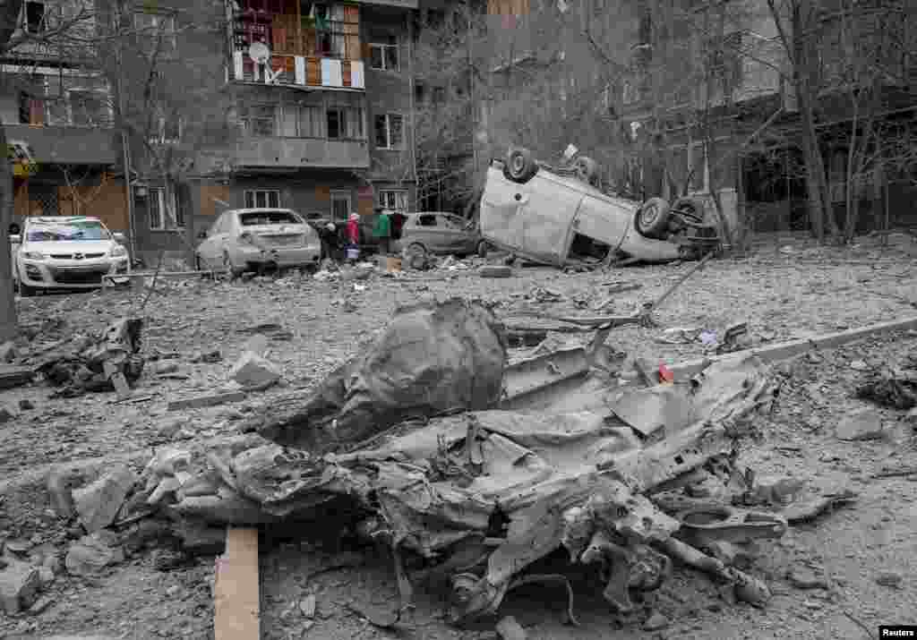 Local residents stand near their apartment building and cars damaged during a Russian missile strike, amid Russia&#39;s attack on Ukraine, in Kharkiv, Ukraine.