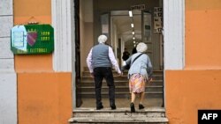 FILE - An elderly couple arrives at a polling station to vote, in Rome, Italy, Sept. 25, 2022. 