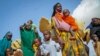 FILE - Somali women and children who fled drought-stricken areas carry their belongings as they arrive at a makeshift camp for the displaced on the outskirts of Mogadishu, Somalia, June 30, 2022. 