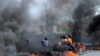 FILE - Motorcycle drivers pass through a burning road block as anger mounted over fuel shortages that have intensified as a result of gang violence, in Port-au-Prince, Haiti, July 13, 2022.