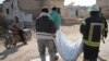 Members of the Syrian Civil Defense, also known as the White Helmets, walk with a body bag of a victim of a reported airstrike in the Syrian village of al-Sahharah in the countryside west of the northern city of Aleppo, Nov. 6, 2019.