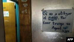 FILE - A sign reads 'If you are going to use the toilet, please bring your water' at the University Hospital in Caracas on July 19, 2018. 