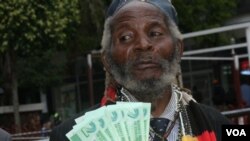 Holding bills of new Zimbabwean money, a man welcomes the introduction of bond notes saying the move will ease cash shortages in the country, in Harare, Zimbabwe, Nov. 28, 2016. (S. Mhofu/VOA)
