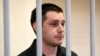 FILE - U.S. ex-marine Trevor Reed, charged with attacking police, stands inside a defendants' cage during a court hearing in Moscow, March 11, 2020. 