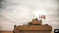 FILE - American soldiers drive a Bradley Fighting Vehicle during a joint exercise with Syrian Democratic Forces at the countryside of Deir Ezzor in northeastern Syria, Dec. 8, 2021.
