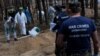FILE - A war crimes prosecutor stands as experts work at a forest grave site during an exhumationin the town of Izium in Kharkiv region, Sept. 18, 2022. 