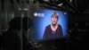 A journalist wearing a face mask as a preventive measure against COVID-19 looks at her mobile phone next to a TV monitor showing a speech by United Nations High Commissioner for Human Rights Michelle Bachelet during World Press Freedom Day in Geneva, May 3, 2022.
