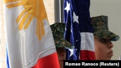 Anggota korps marinir Filipina-AS berdiri tegak dengan bendera Filipina dan Amerika di kota Taguig, metro Manila, Filipina. (Foto: Reuters)